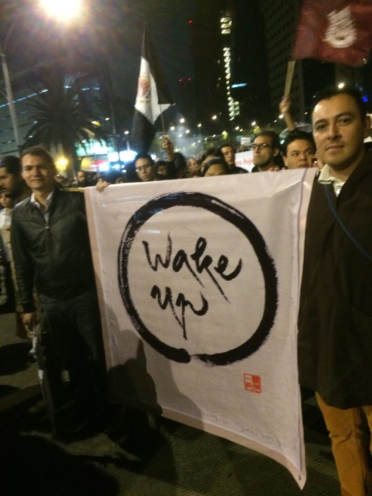 Rogelio (right), holding Wake Up Banner in a Peace March